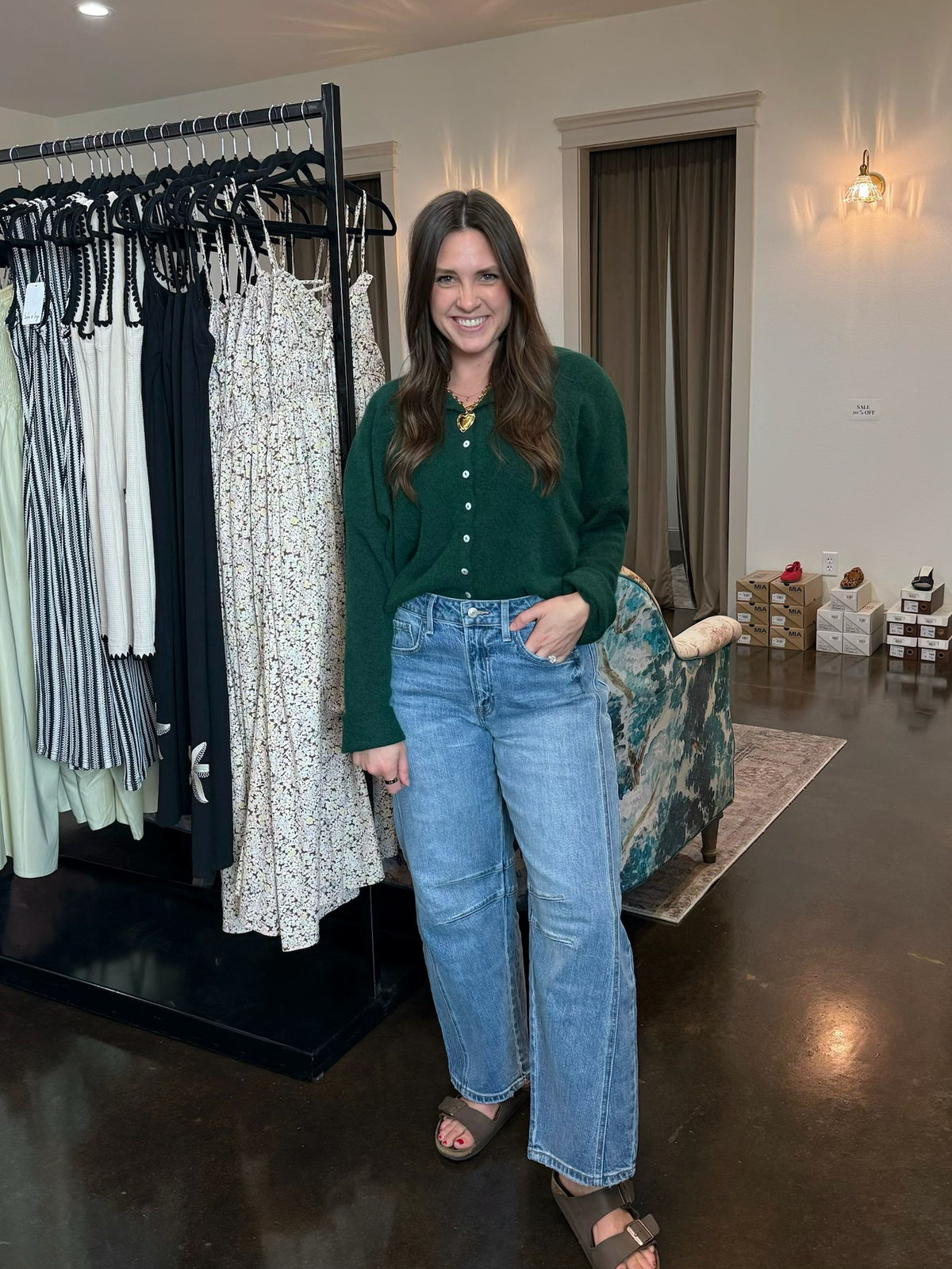 Laura wearing Huda high rise barrel jeans in medium blue stretch denim with a curved wide leg, paired with the piper cardigan.